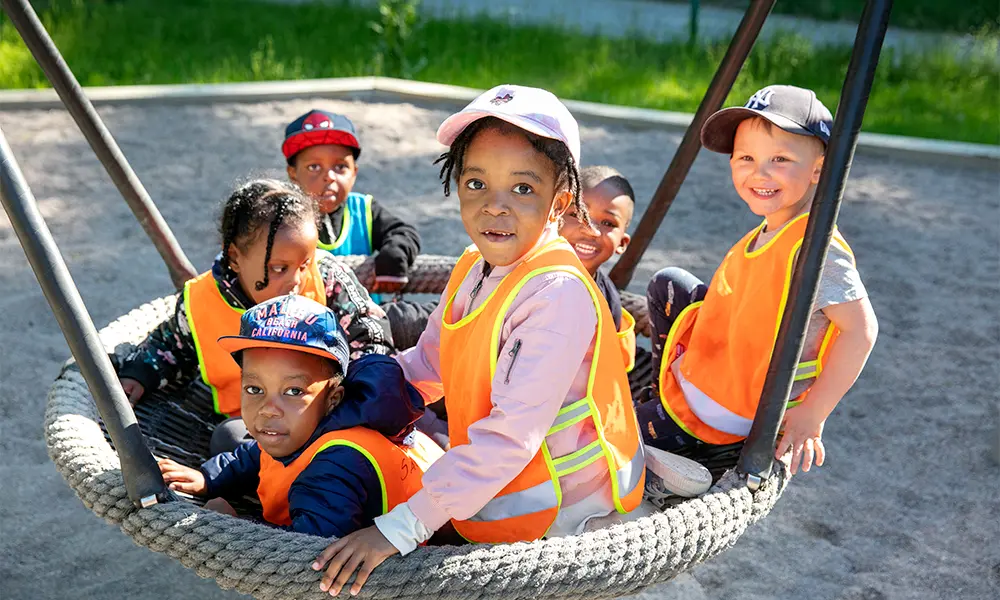 Foto på sex barn som sitter i en gunga tillsammans.